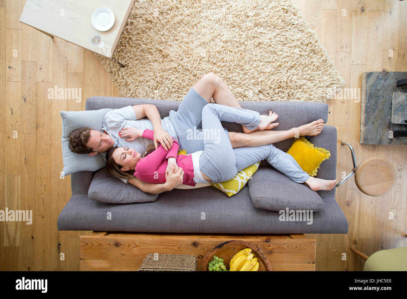 Mid adult couple are cuddled up together on the sofa while they nap. Stock Photo
