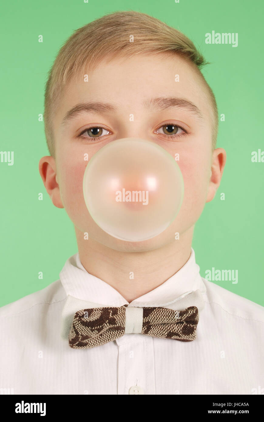 Boy blowing a bubblegum bubble isolated on green Stock Photo