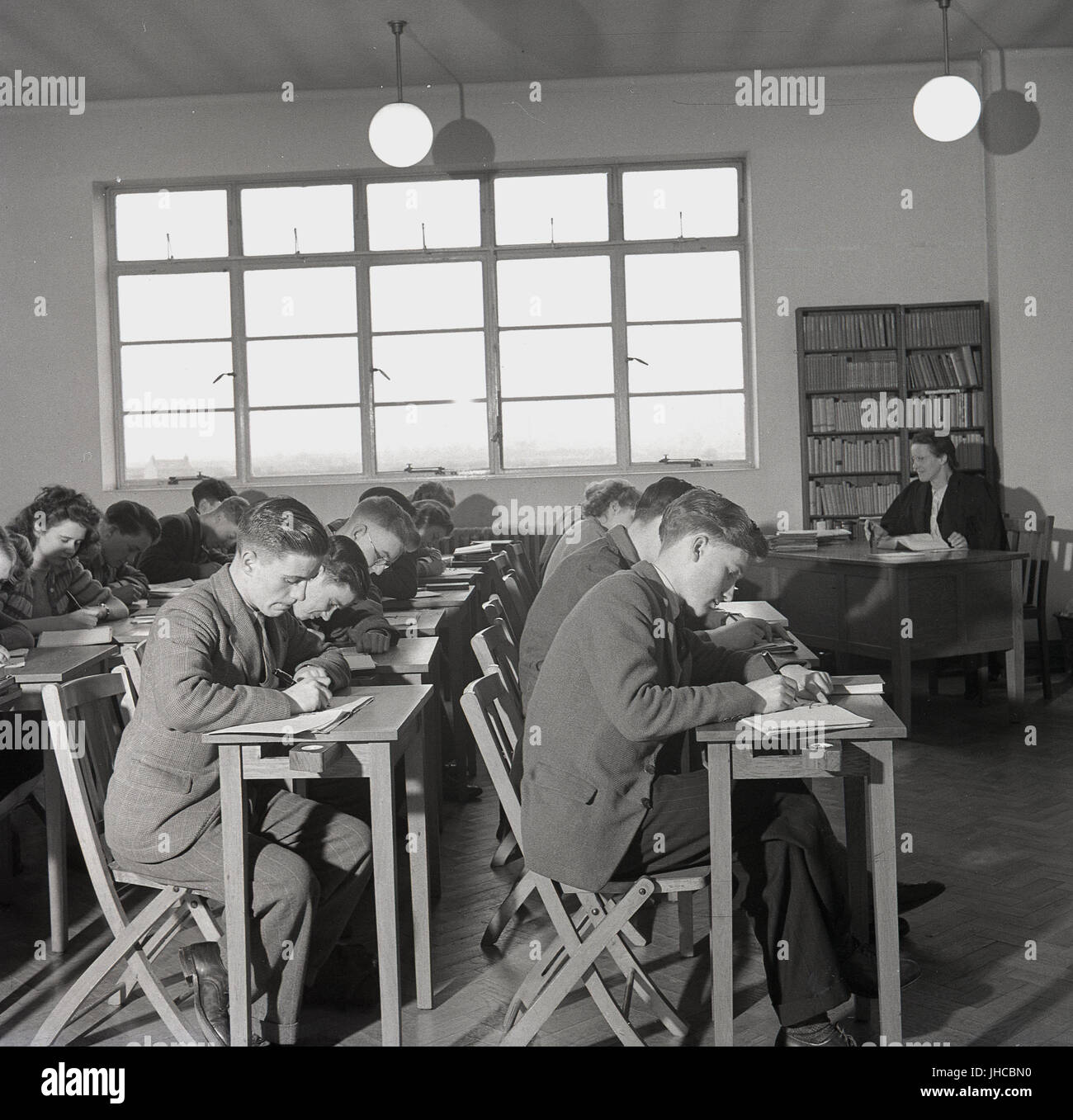 1950s, historical, students sitting in a line at small desks in a classroom taking down notes, England, UK. Stock Photo