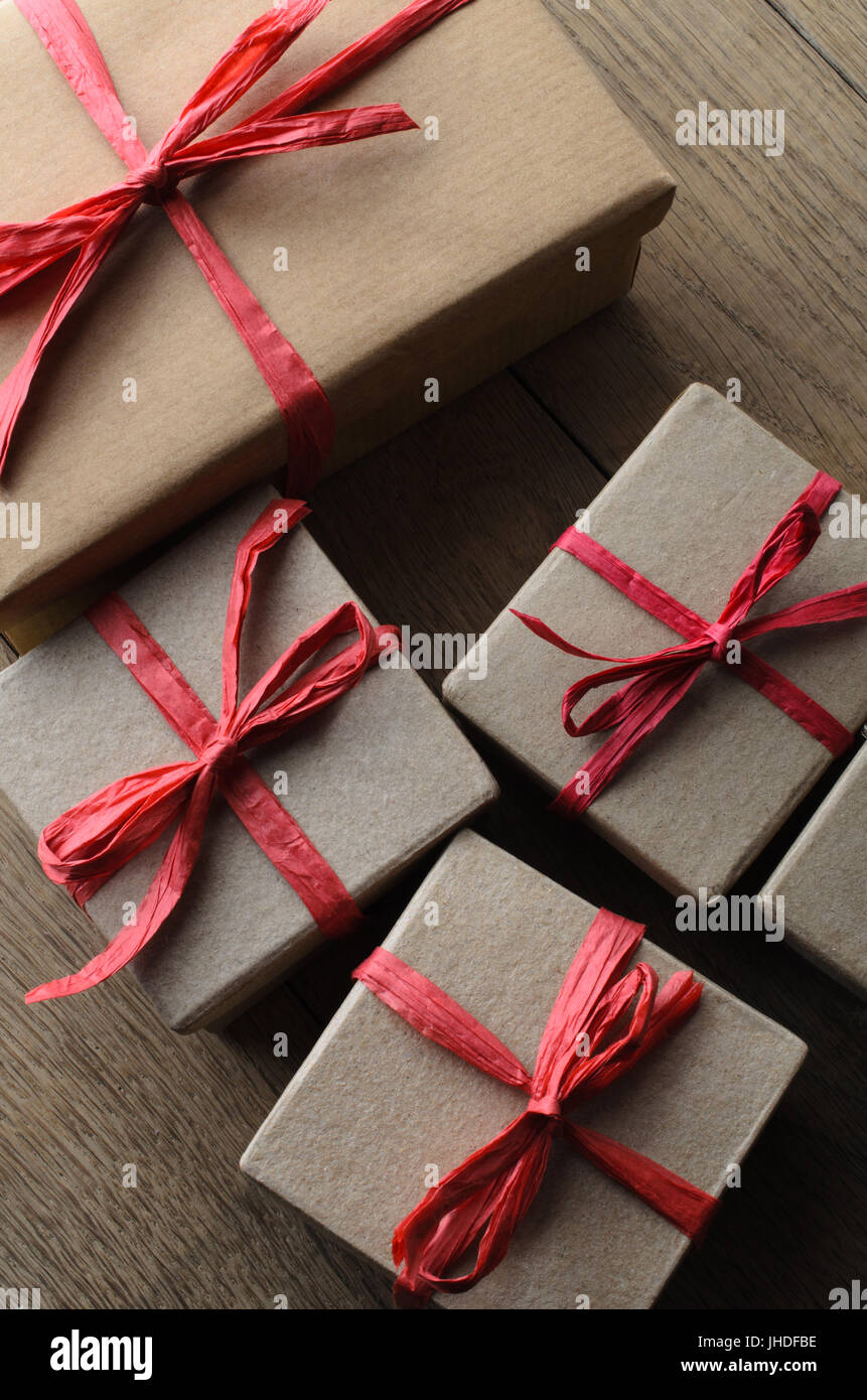 Overhead shot of multiple simple, lidded boxes tied with red raffia ribbon  bows and string. One has a blank tag for your message. Oak plank table bel  Stock Photo - Alamy