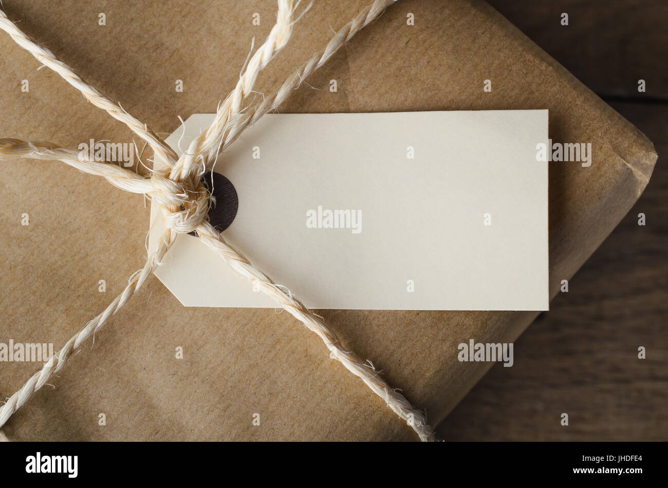 Overhead close up of a blank parcel label, tied with string to a package wrapped in plain brown paper. Stock Photo