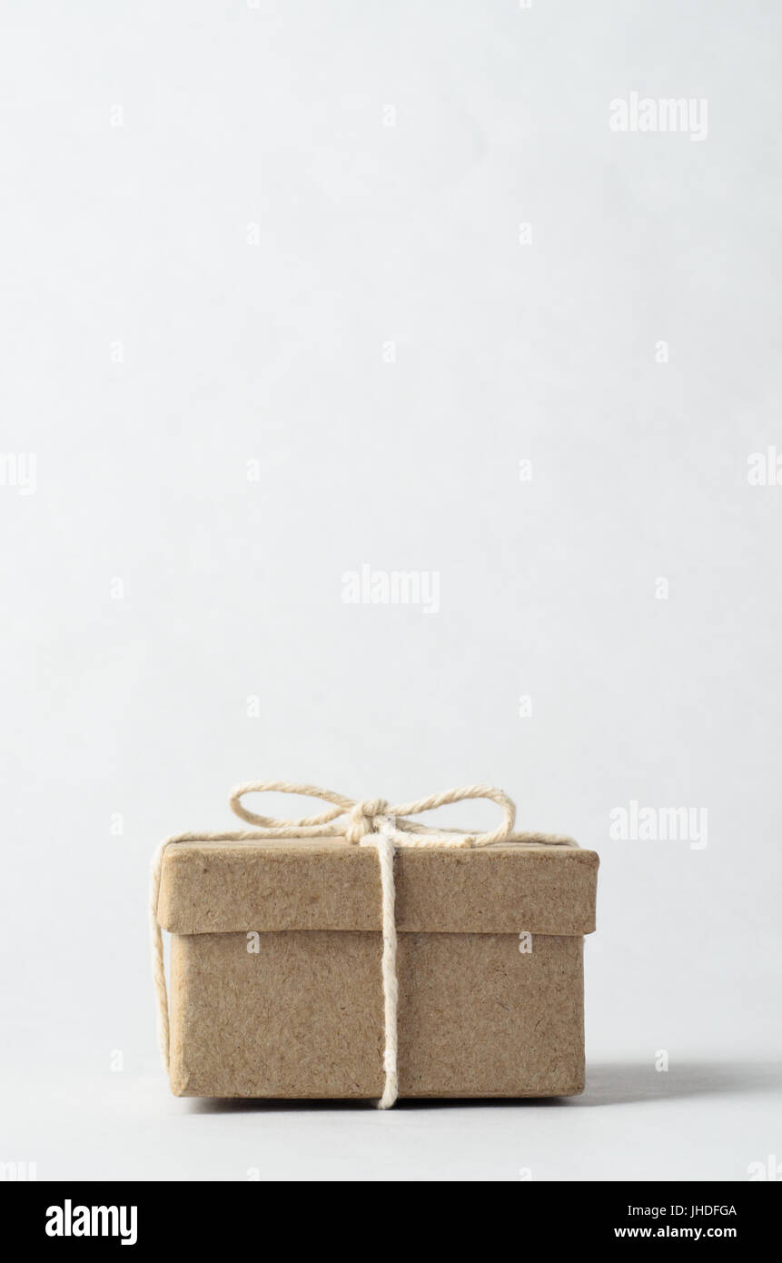 Simple brown box with closed lid, tied to a bow with string, signifying a gift, surprise or secret. Stock Photo