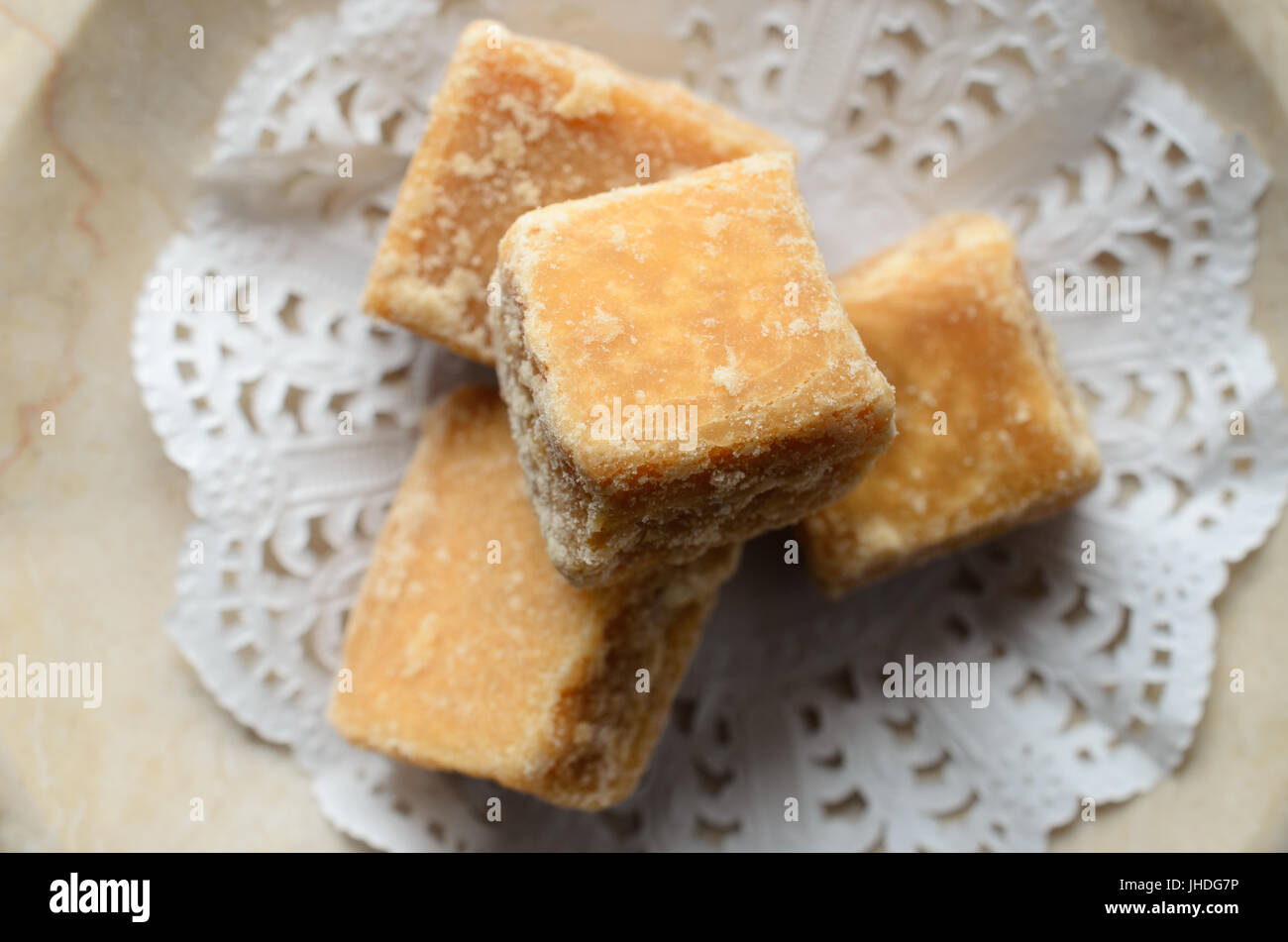 Overhead close up of fudge cubes, carefully arranged on a decorative white paper doily in a soapstone dish. Stock Photo