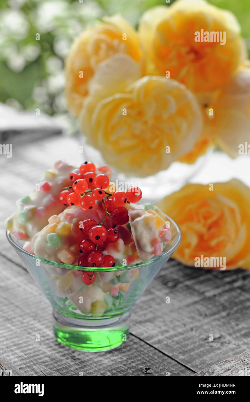 White cake with candied fruits and red currants in a green transparent ...