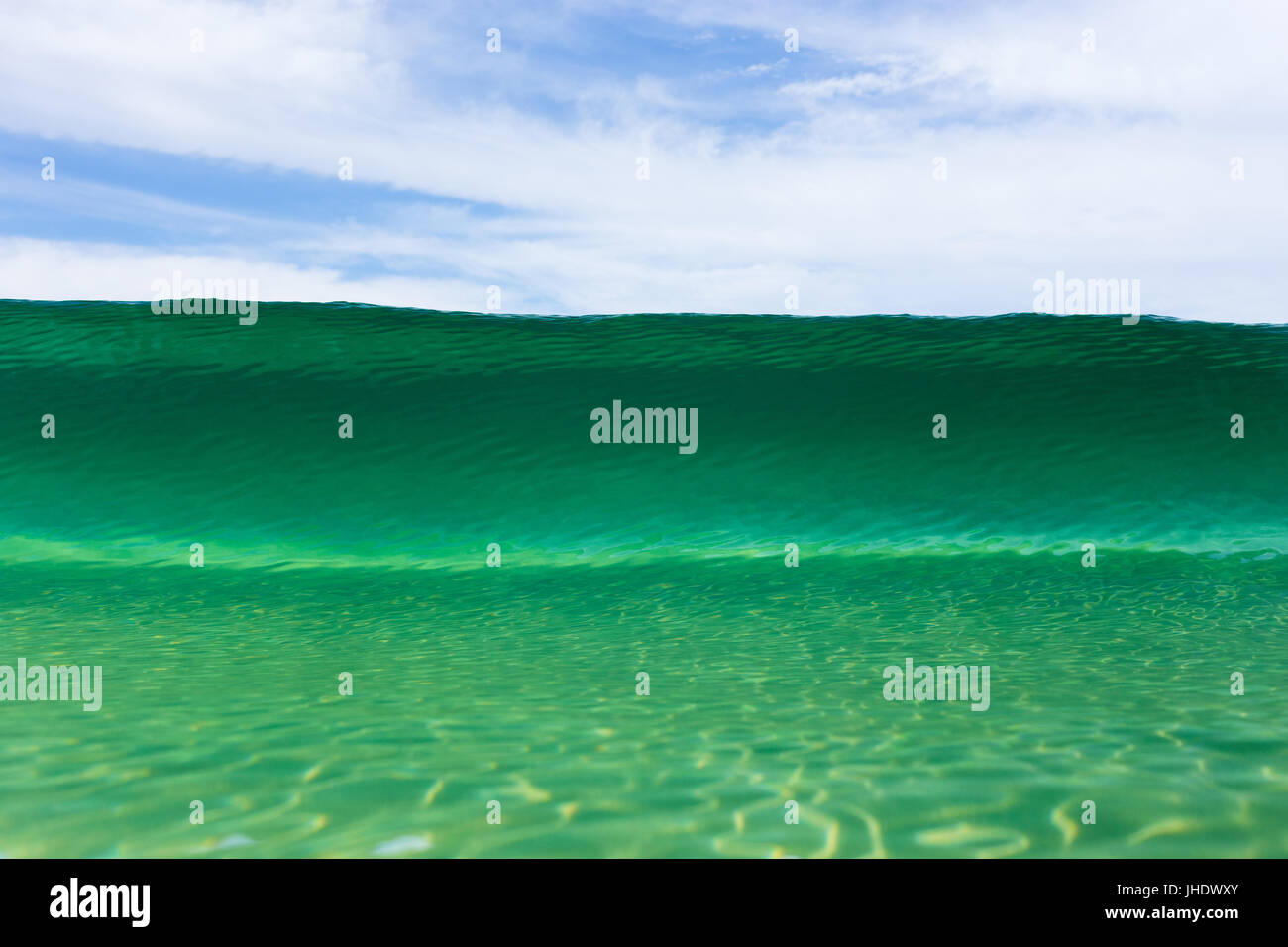 A beautiful emerald wave crests at an Australian beach on a bright summer day. Stock Photo