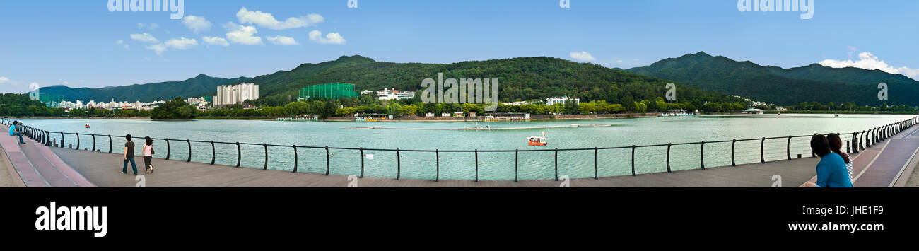 people resting by lake in city park with mountains in back in Daegu, south korea Stock Photo