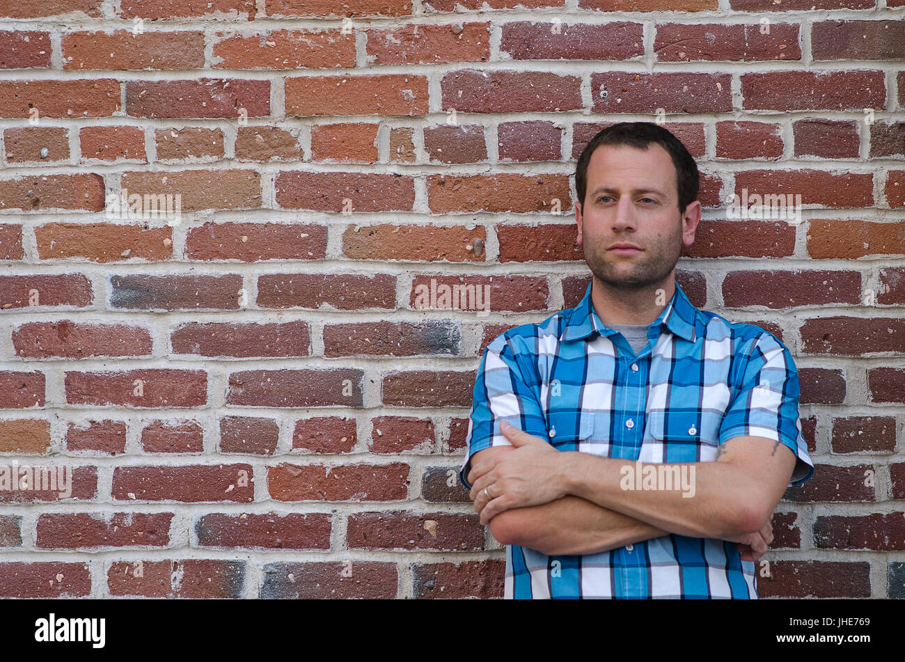 Optimistic Man Leaning Against A Brick Wall Stock Photo - Alamy