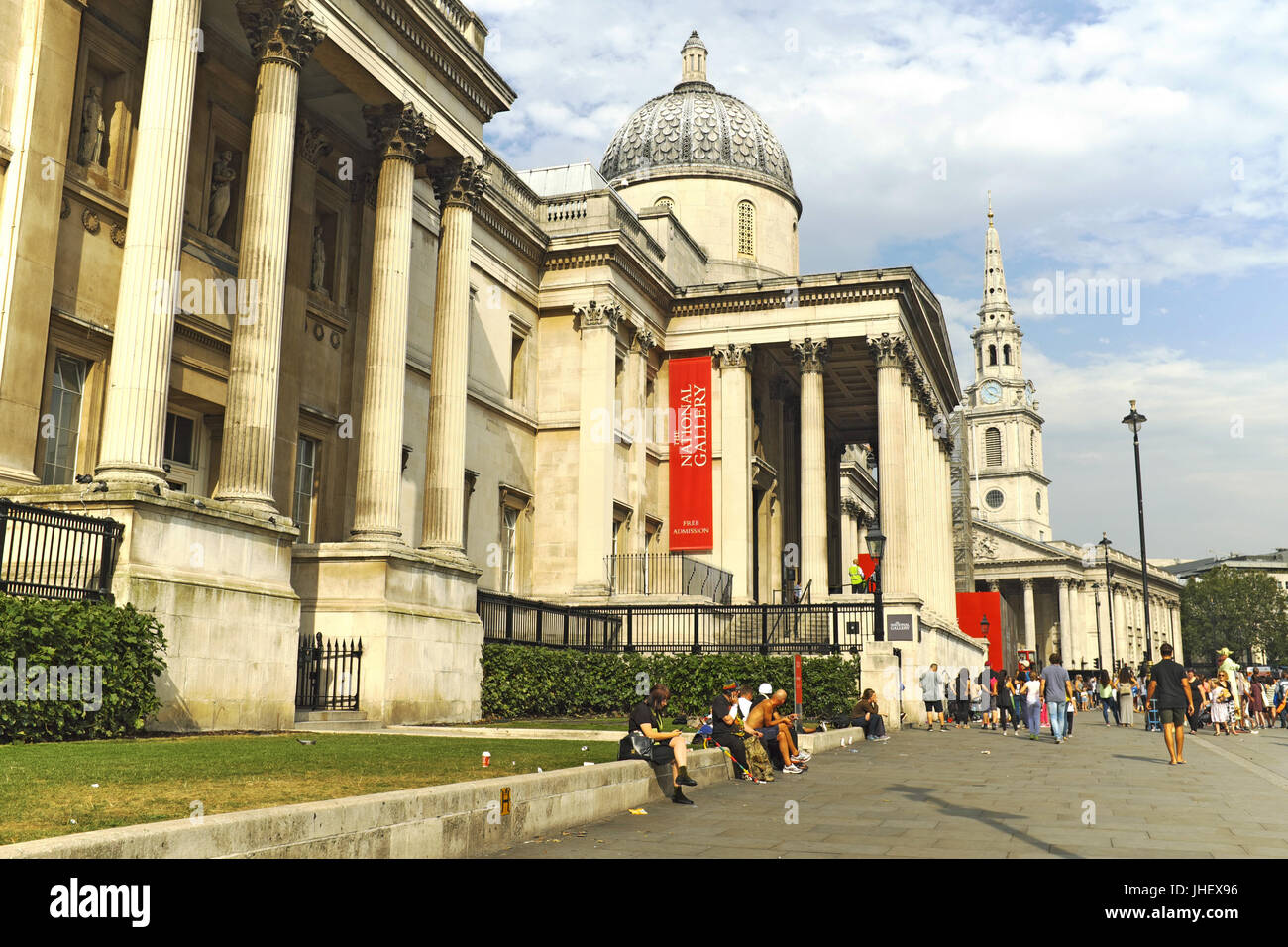 People sit outside the National Gallery on Trafalgar Square in London, England on an August afternoon. Stock Photo