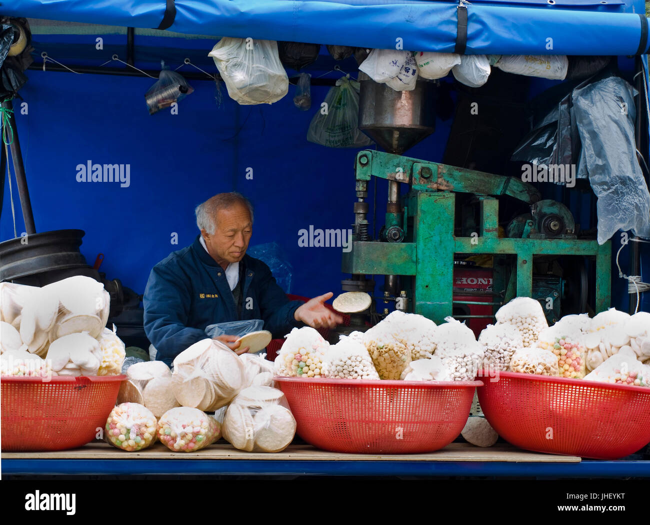 old korean man making corn flat bread for sale Stock Photo
