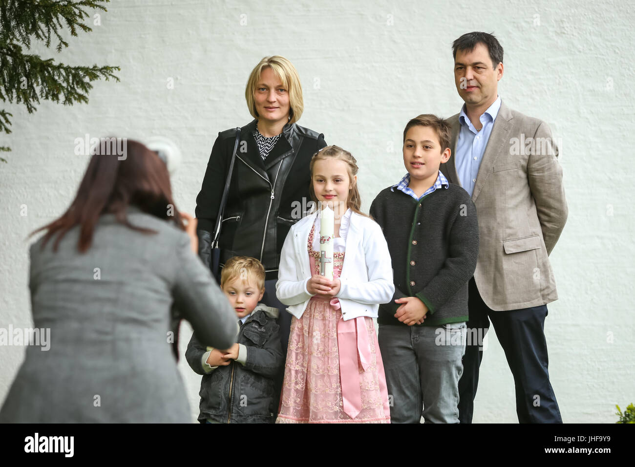 NANDLSTADT, GERMANY - MAY 7, 2017 : A young girl with candle posing with her family to a photographer at the first communion in Nandlstadt, Germany. Stock Photo