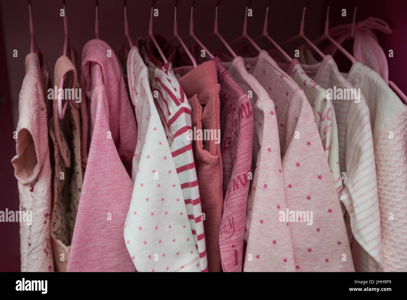 A lot of white children's clothes on hangers. Children's wardrobe with