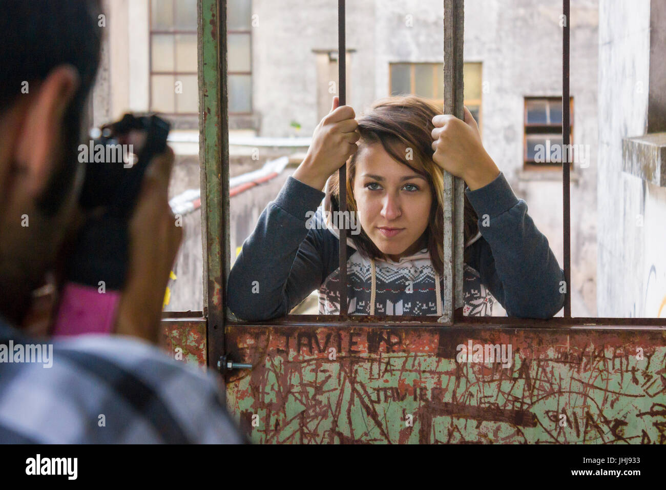 Young woman looking from behind the bars Stock Photo