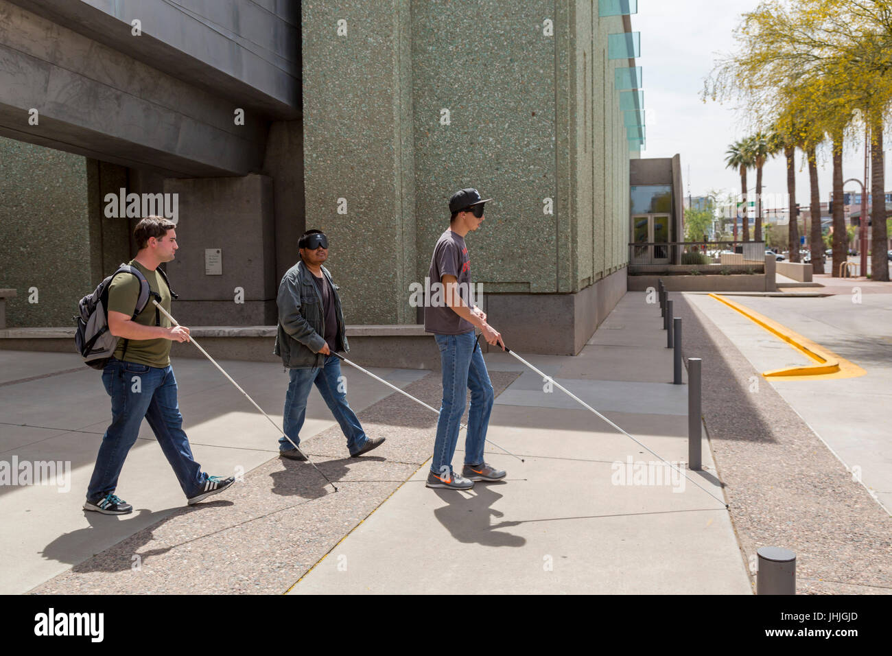 Phoenix, Arizona - Blind and visually impaired young men, some wearing sleep masks, practice navigating city streets with white canes. Stock Photo