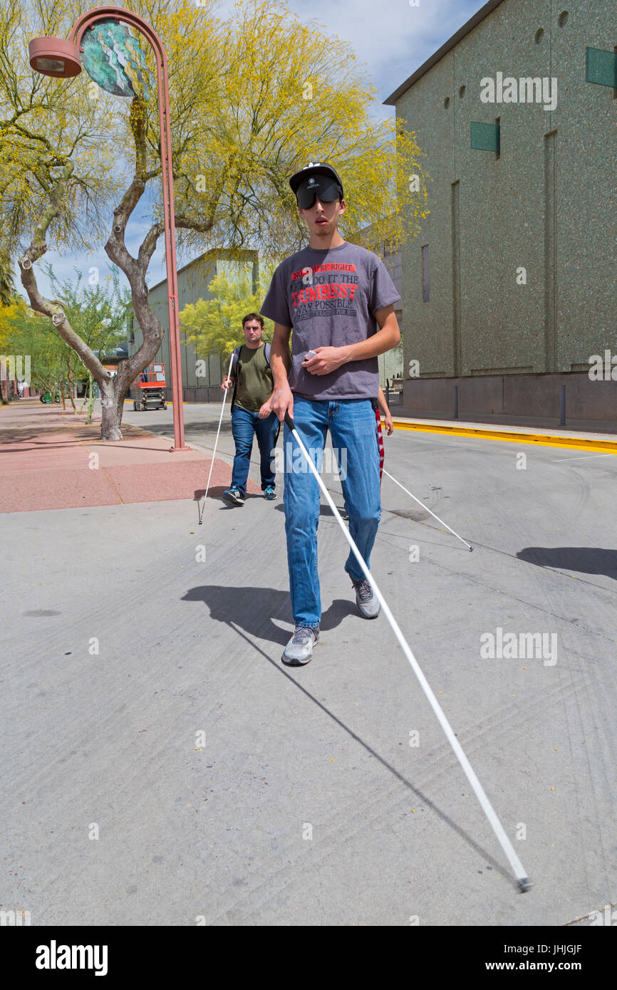 Phoenix, Arizona - Blind and visually impaired young men, some wearing sleep masks, practice navigating city streets with white canes. Stock Photo