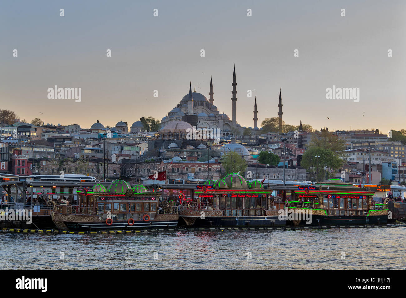 Istanbul, Turkey - April 25, 2017: Traditional fast food bobbing boats serving fish sandwiches at Eminonu district with Rustem Pasha Mosque and Suleym Stock Photo