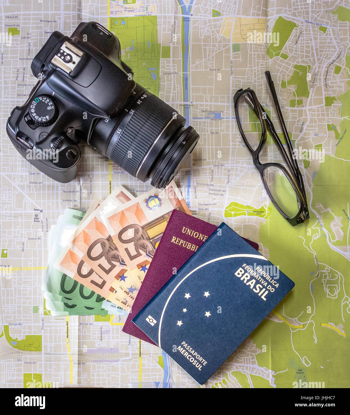 Planning a trip - Brazilian and Italian passports on city map with euro bills money, camera and glasses Stock Photo