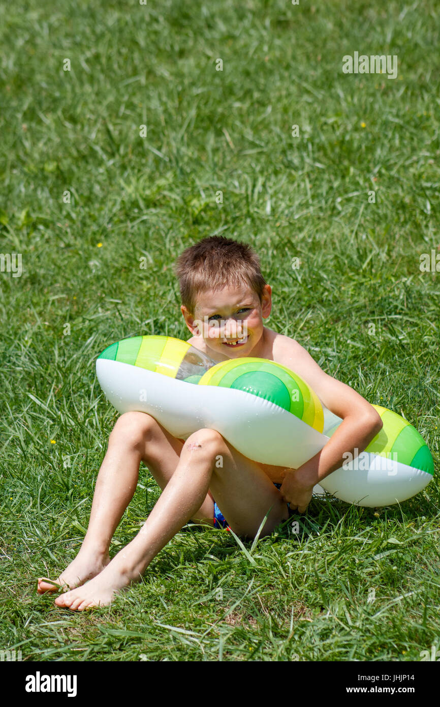 Boy sitting in swim ring on grass Stock Photo Alamy