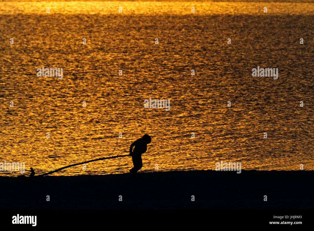 Golden sunset. Seaside. Silhouettes of children. Stock Photo