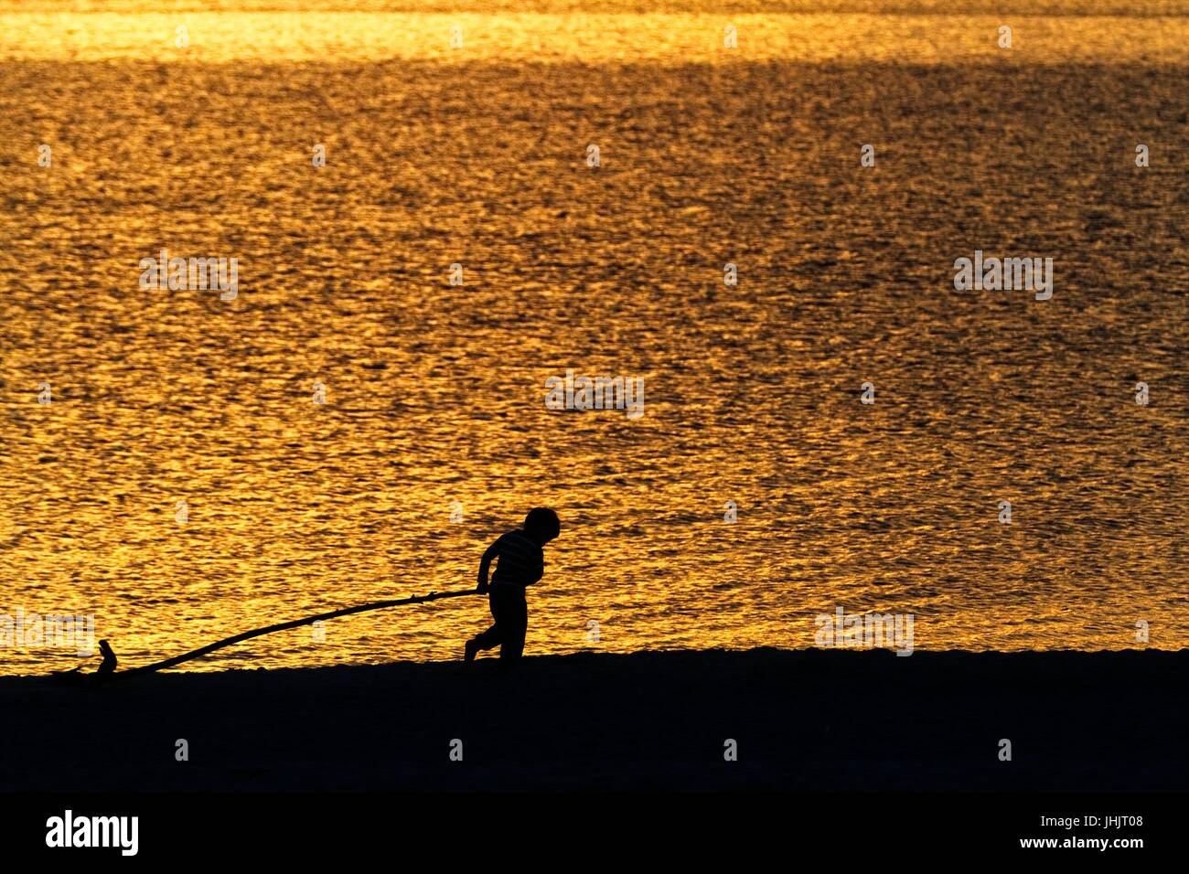 Golden sunset. Seaside. Silhouettes of children. Stock Photo