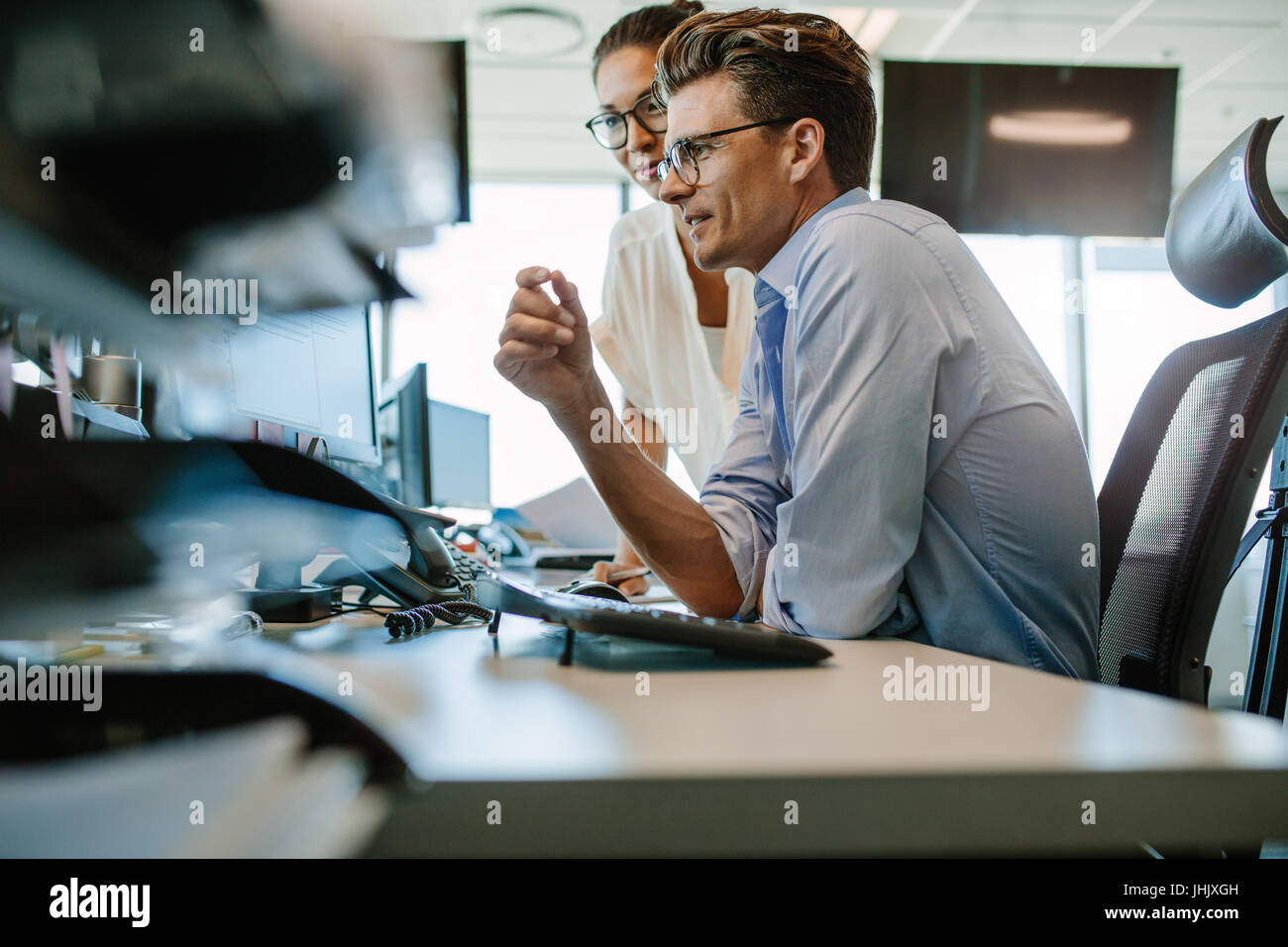 Side view of a mature businessman and businesswoman working together on desktop computer. Two business professionals looking at computer monitor. Stock Photo