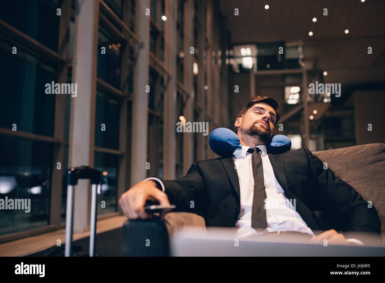 Traveler waiting at airport after flights delays and cancellations. Businessman asleep in airport lounge. Stock Photo