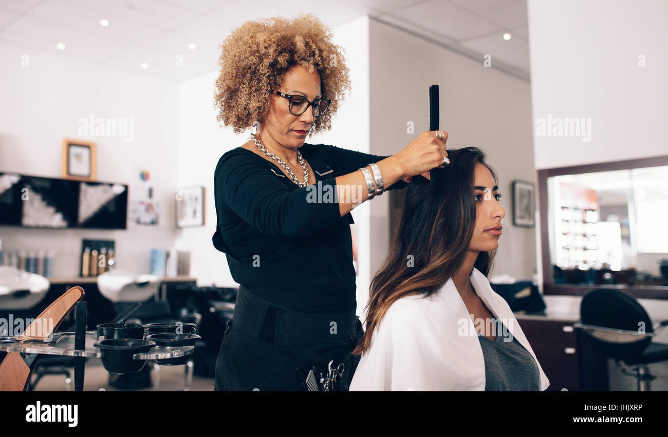 Female hair stylist working on a woman 's hair. Woman hairdresser serving her customer at the salon. Stock Photo