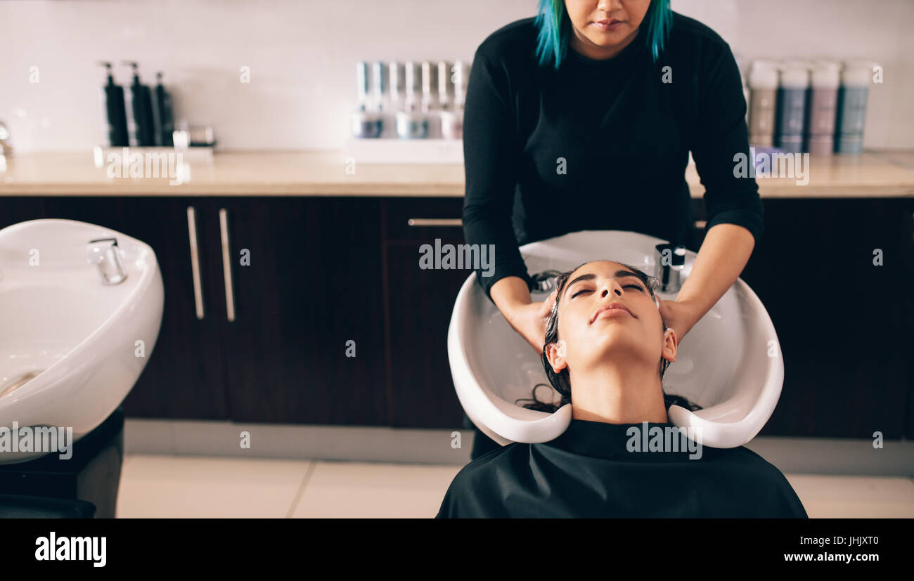 Hairdresser giving hair wash service to a customer at the salon. Woman getting hair care treatment  done in a beauty salon. Stock Photo
