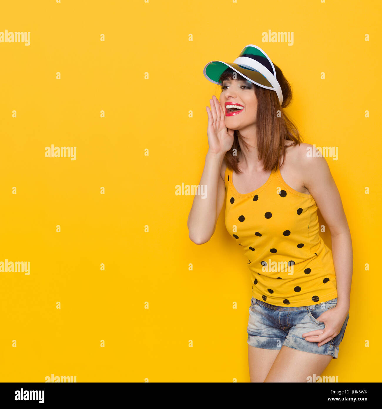 Delighted beautiful young woman in sunglasses turquoise bra and jeans shorts  posing with arms raised and looking up. Three quarter length studio shot  Stock Photo - Alamy