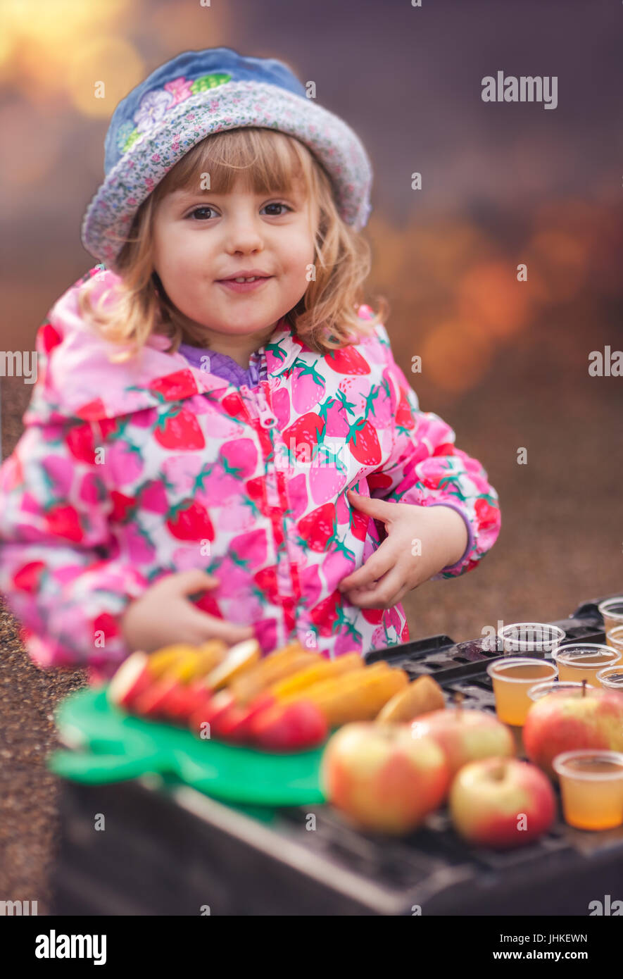 Portrait of a cute little girl tasting fresh organic apple juice at a