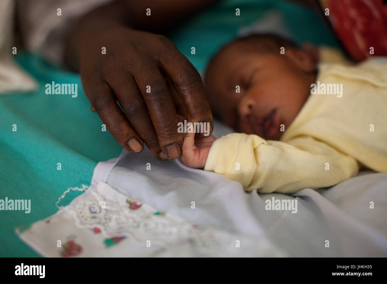 A mothers hand holding the hand of her newly born baby on the ward at Kitovu Hospital. Stock Photo