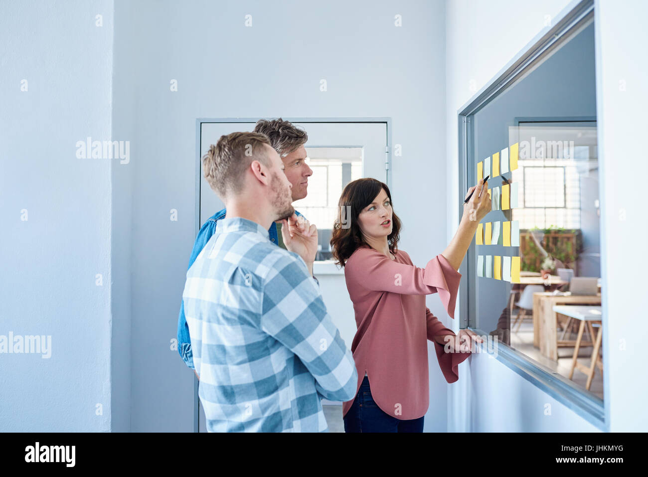 Focused colleagues brainstorming with sticky notes in a modern office Stock Photo