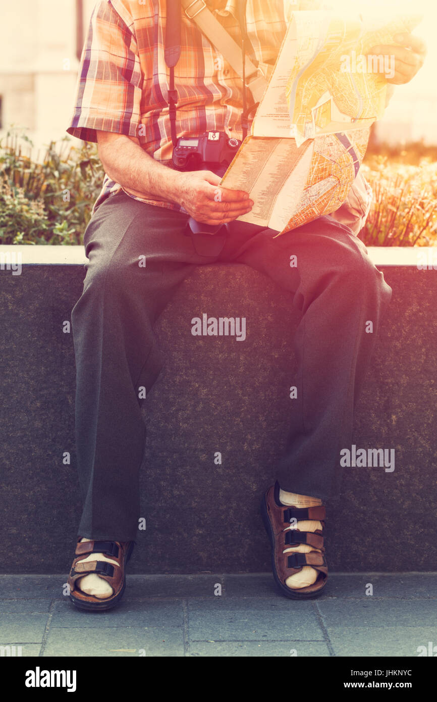 Old pensioner in socks and sandals searching destination on map in park vintage Stock Photo