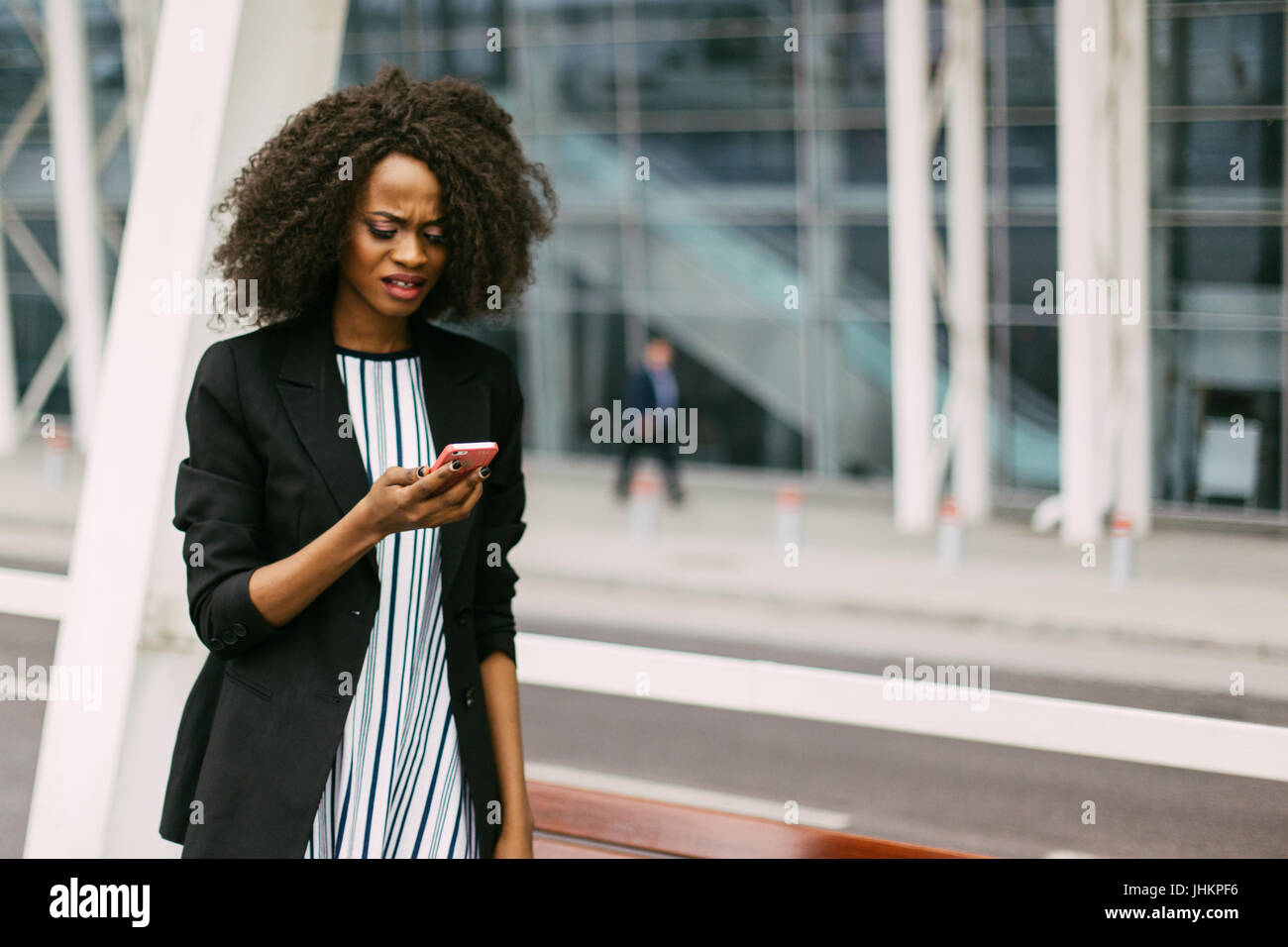 Upset afro-american woman is looking at the mobile phone. Close-up portrait. Stock Photo