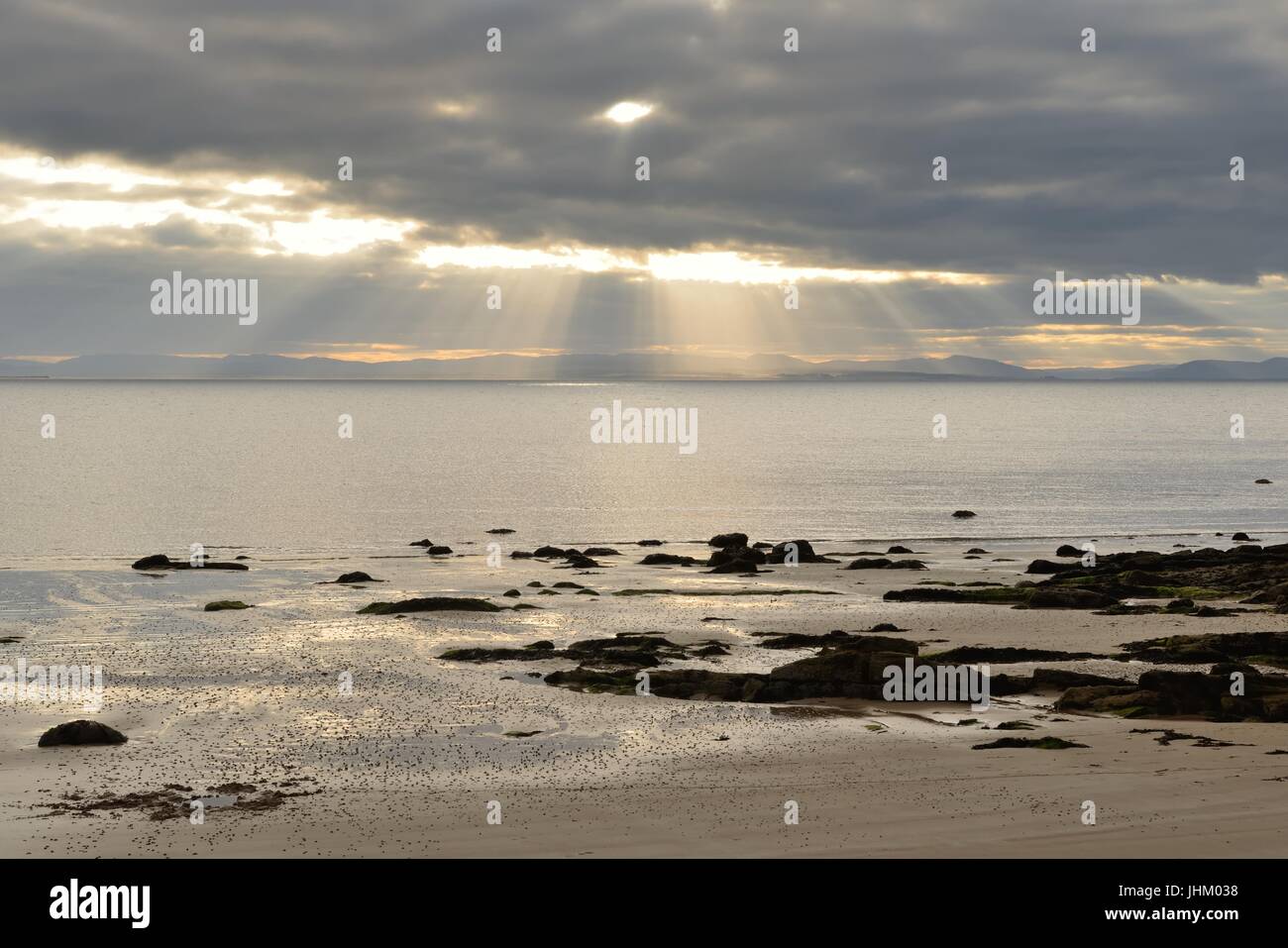 Evening sunlight breaks through dark clouds over the Dornoch firth at Portmahomack in Easter Ross, Scotland. Stock Photo