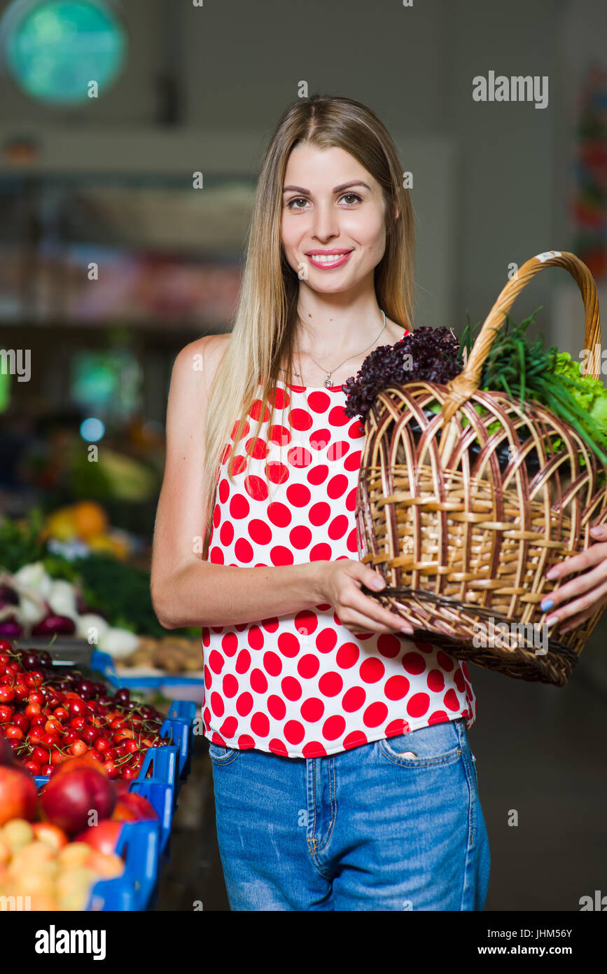 Portrait of a girl with a basket of vegetables. Beautiful blond young girl with a full basket of