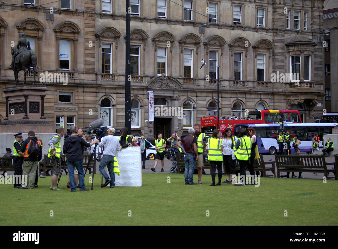 Glasgow, Scotland, UK. 14th July. Filming was nonchalantly ignored today by locals now getting used to media and film crews in the city as people passed their lunchtime with the latest series of  the BBC Scotland spoof police comedy “Scot squad” was being shot in the city's George Square, Credit: gerard ferry/Alamy Live News Stock Photo