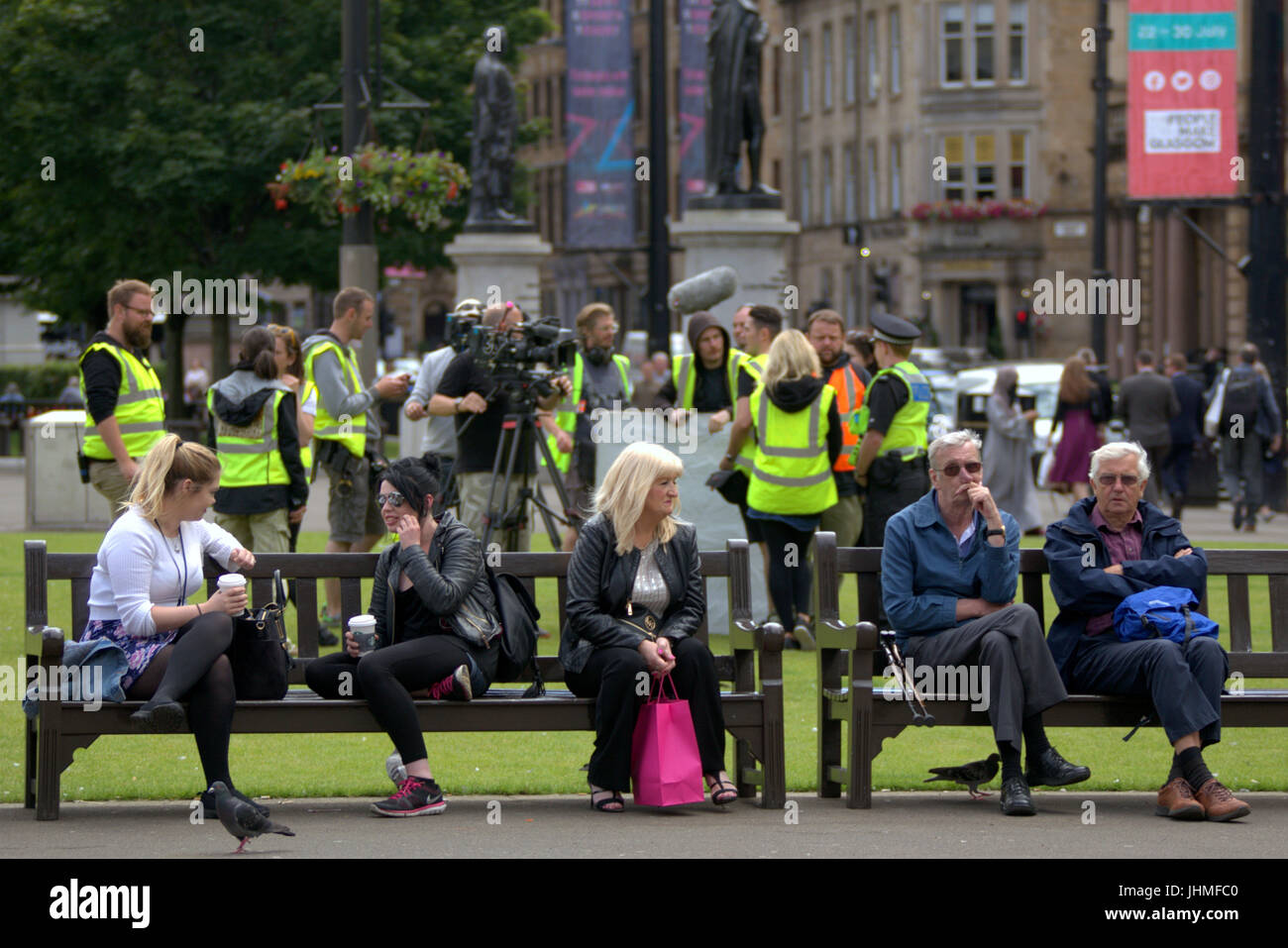 Glasgow, Scotland, UK. 14th July. Filming was nonchalantly ignored today by locals now getting used to media and film crews in the city as people passed their lunchtime with the latest series of  the BBC Scotland spoof police comedy “Scot squad” was being shot in the city's George Square, Credit: gerard ferry/Alamy Live News Stock Photo