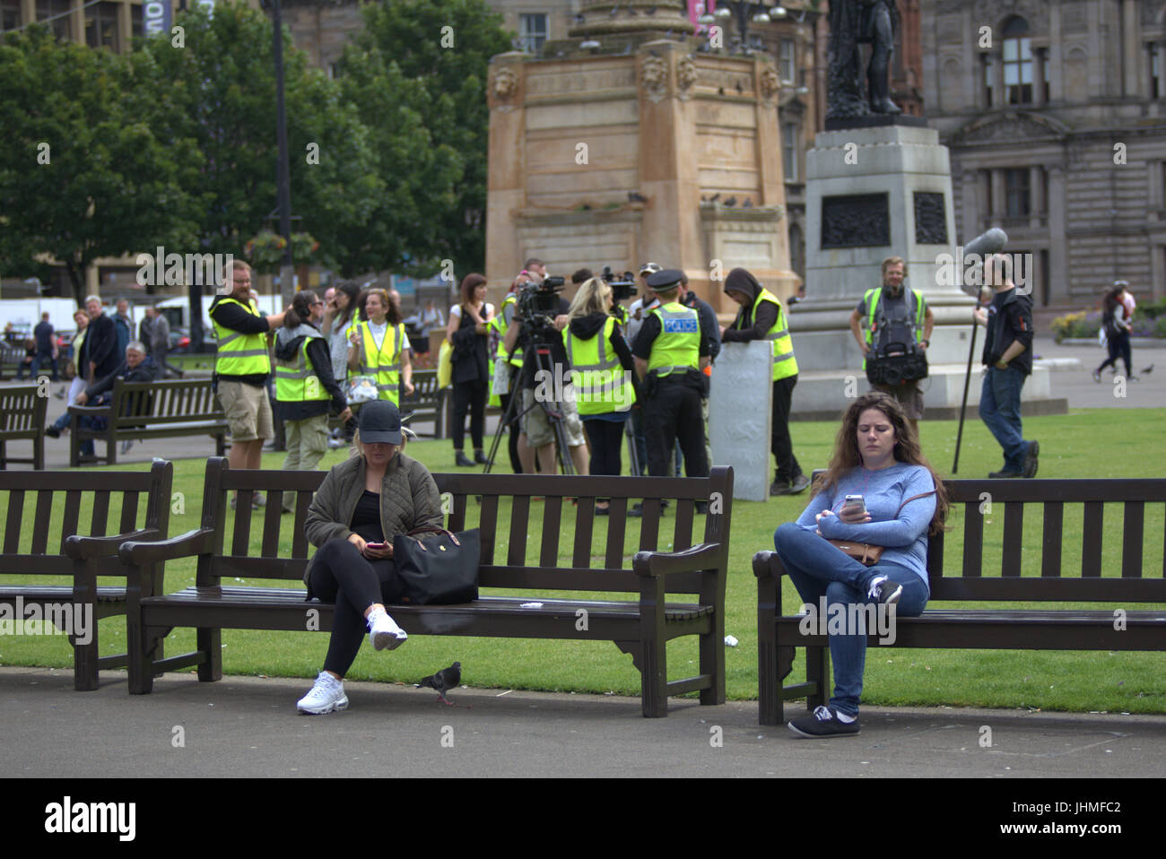 Glasgow, Scotland, UK. 14th July. Filming was nonchalantly ignored today by locals now getting used to media and film crews in the city as people passed their lunchtime with the latest series of  the BBC Scotland spoof police comedy “Scot squad” was being shot in the city's George Square, Credit: gerard ferry/Alamy Live News Stock Photo