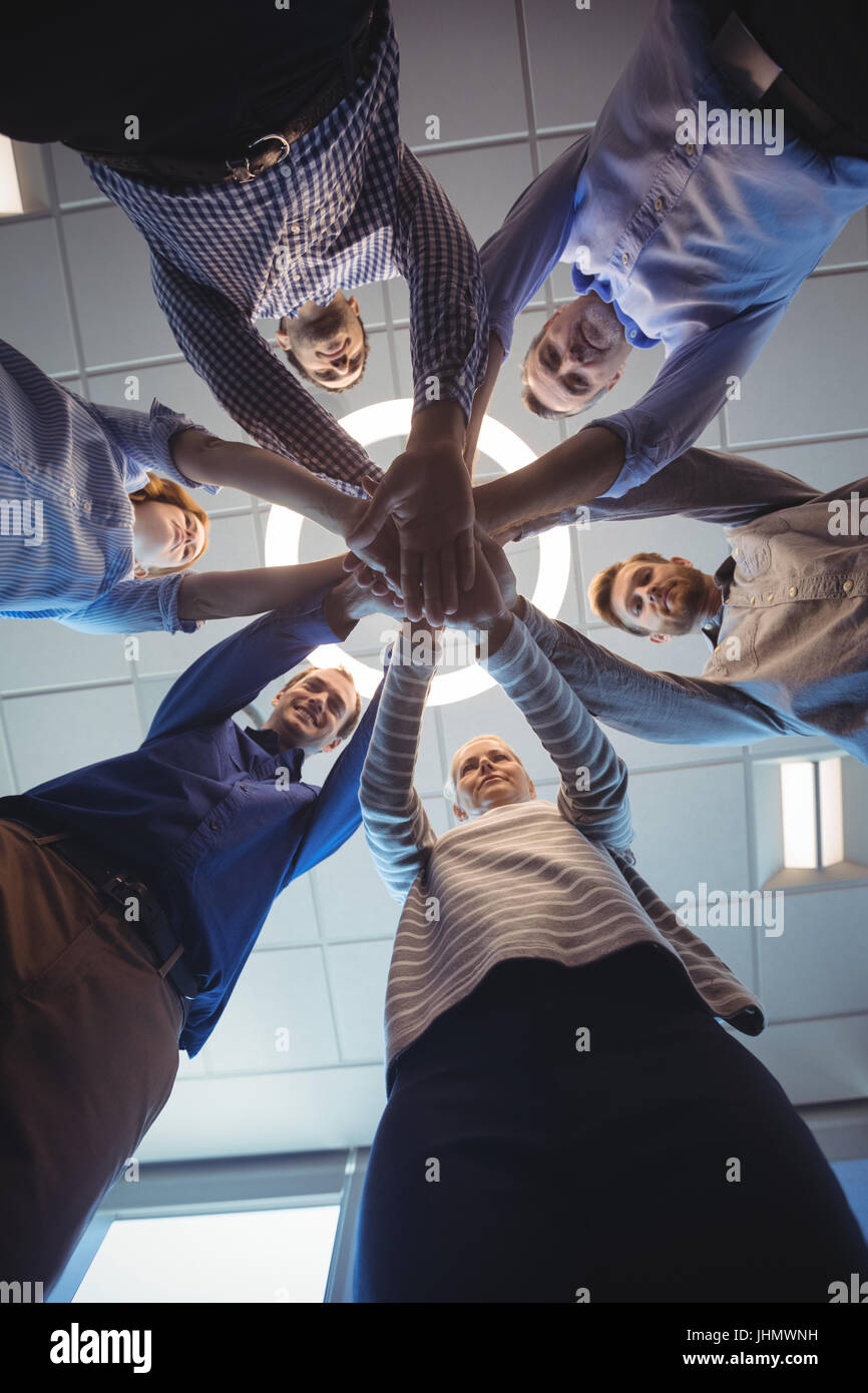 Directly below shot of business colleagues stacking hands against ceiling at office Stock Photo