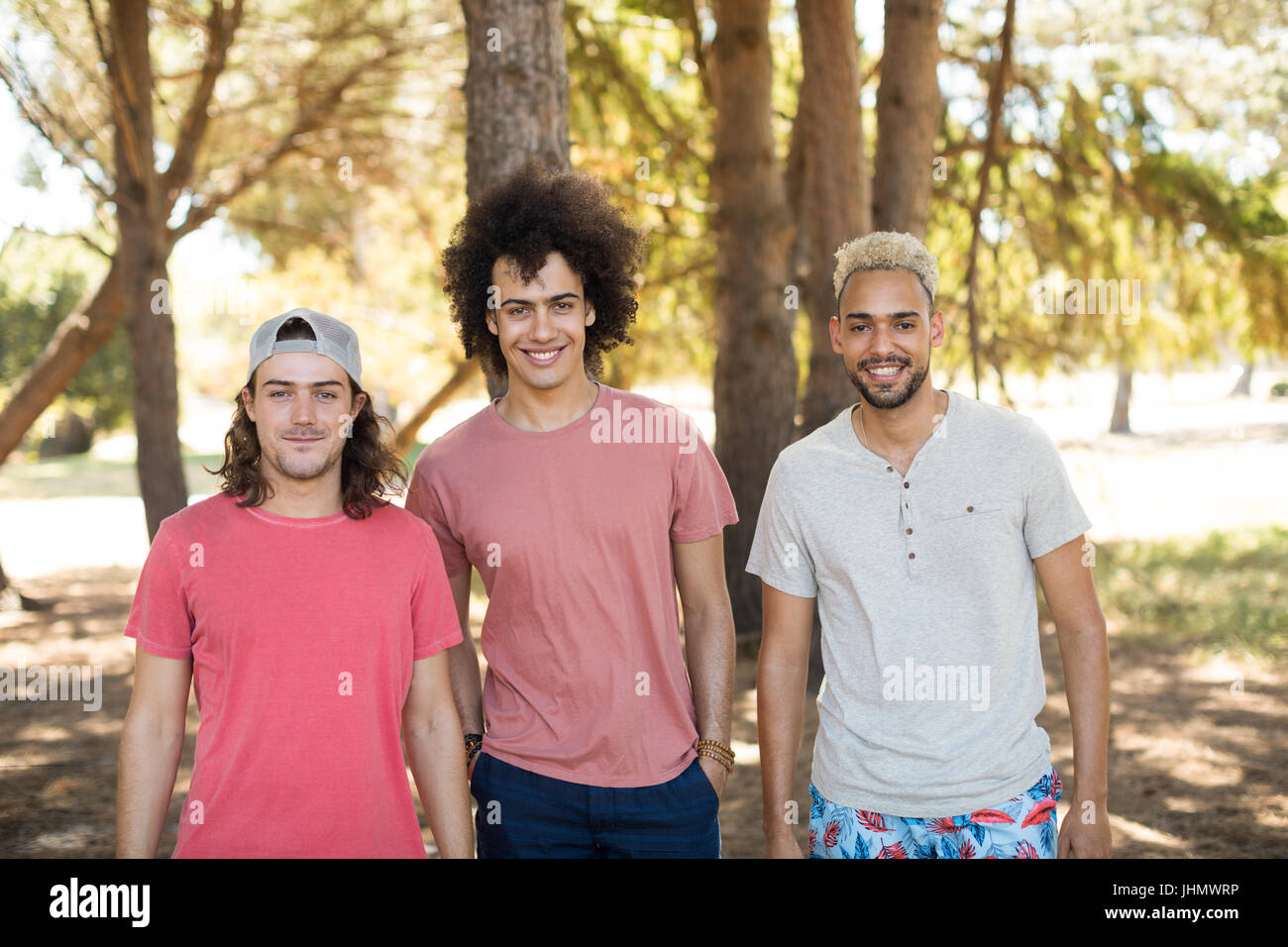 Portrait of smiling male friends standing side by side at forest Stock Photo