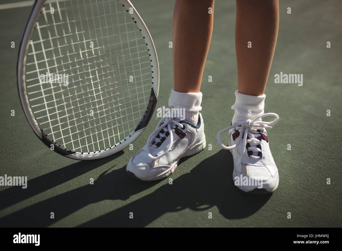 Low section of girl with tennis racket standing on court Stock Photo ...
