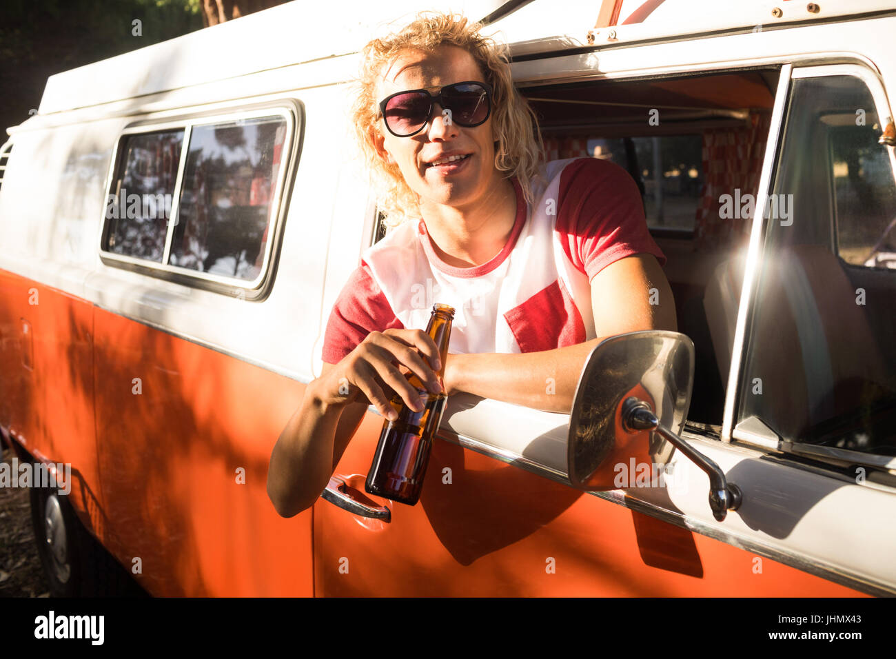 Portrait of man with beer leaning on camper van window Stock Photo