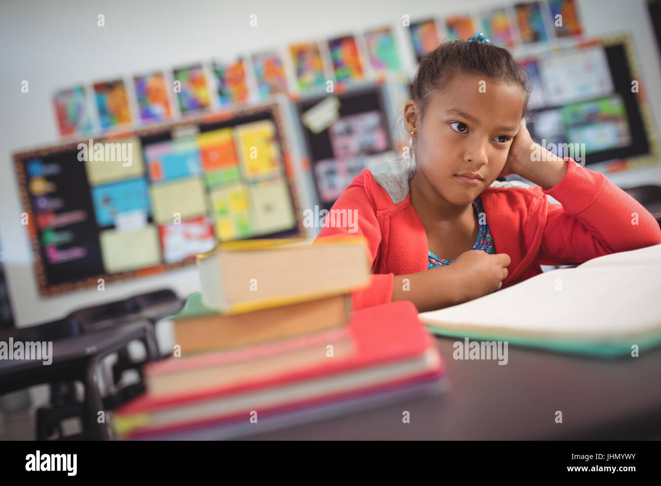 Thoughtful schoolgirl sitting at desk in classroom Stock Photo - Alamy