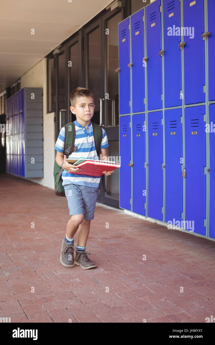 Full length of boy carrying books in corridor at school Stock Photo - Alamy