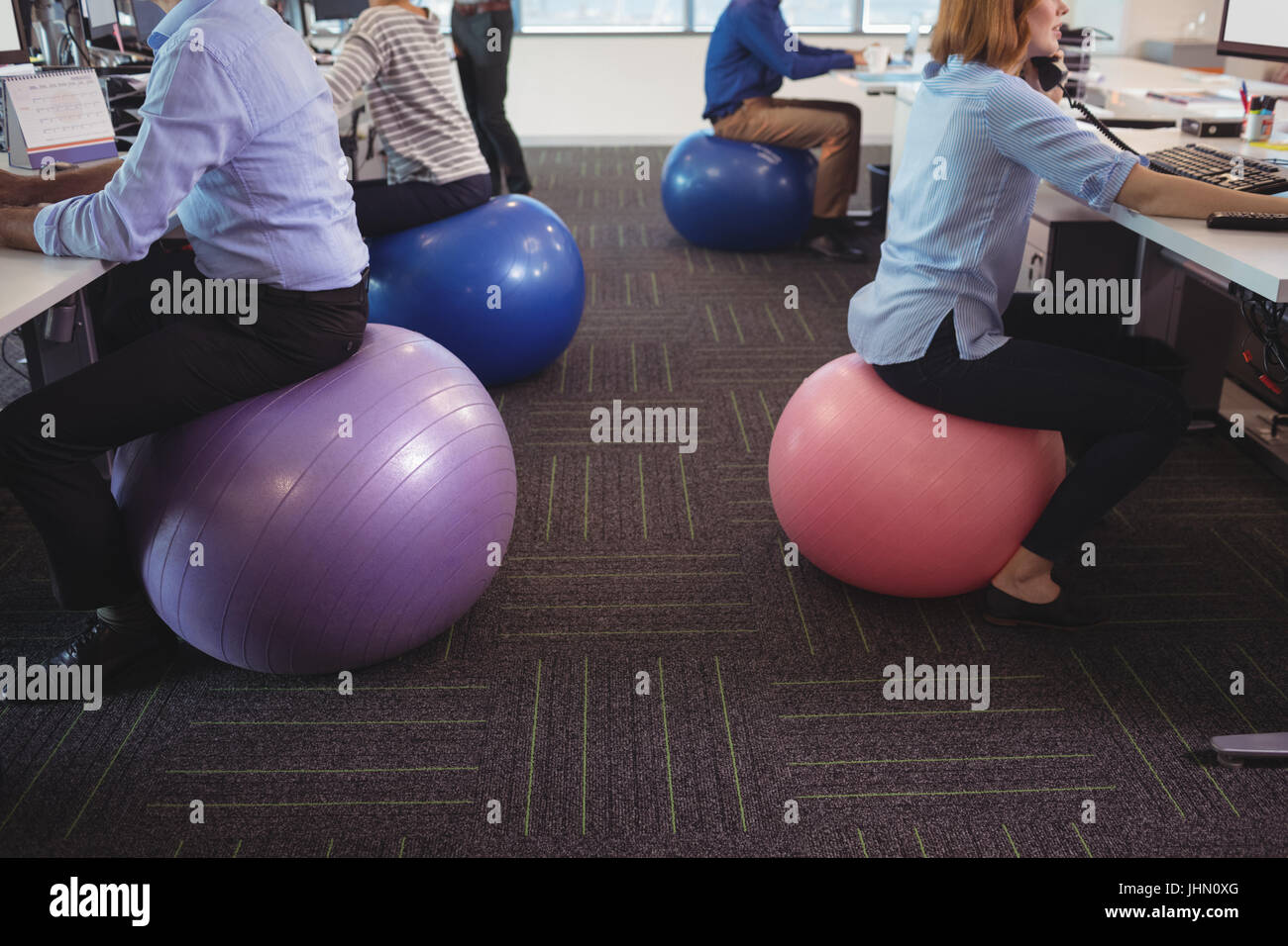 Low Section Of Business People Sitting On Exercise Balls While