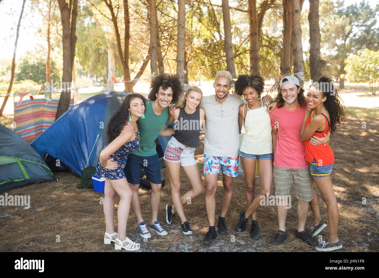 Portrait of smiling friends standing side by side at campsite Stock Photo