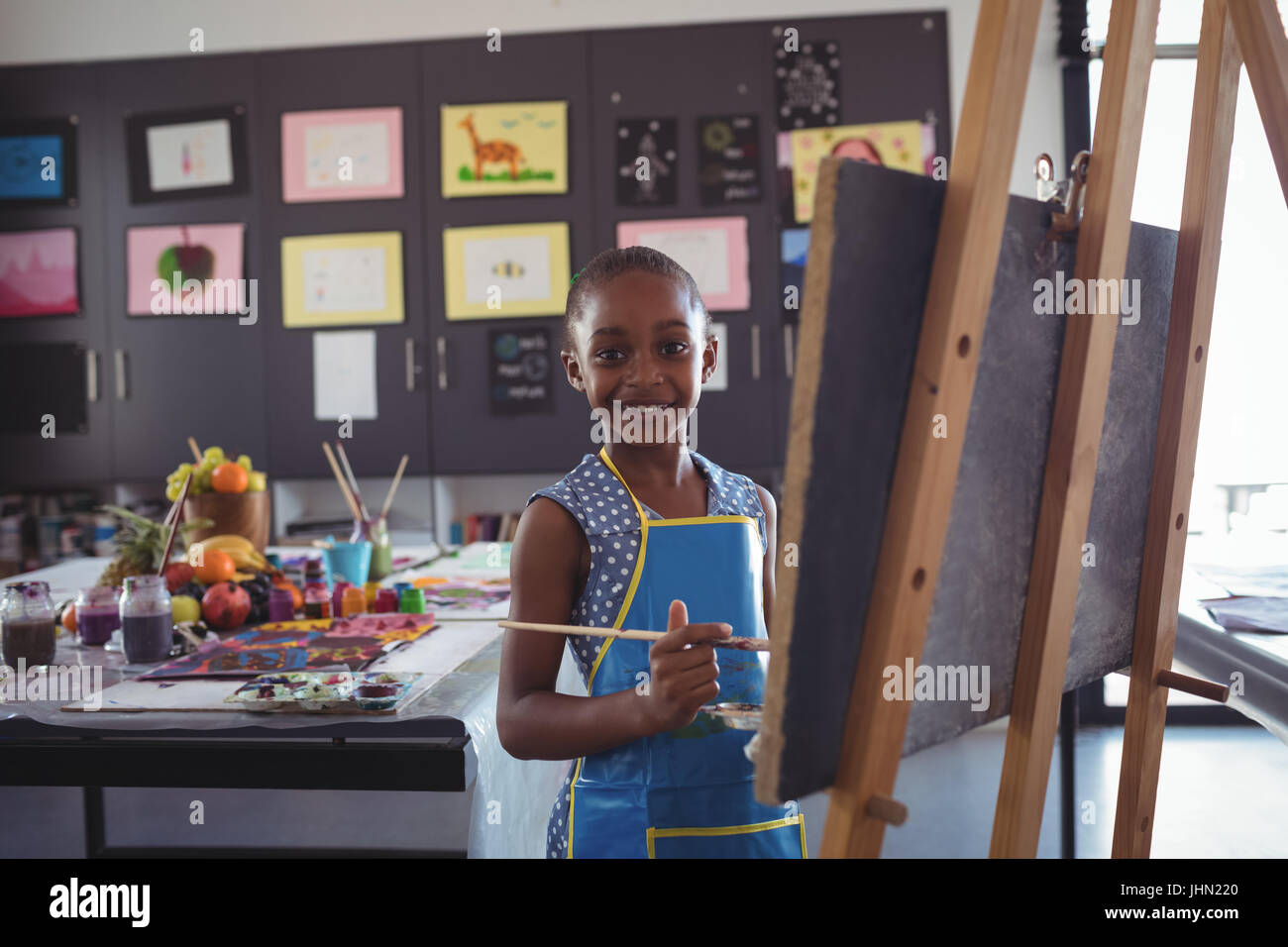 Portrait of smiling girl painting on canvas in classroom Stock Photo ...