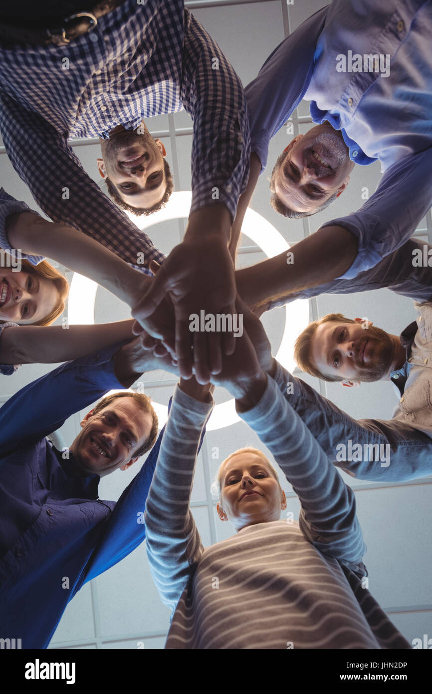 Directly below portrait of business colleagues stacking hands against ceiling at office Stock Photo