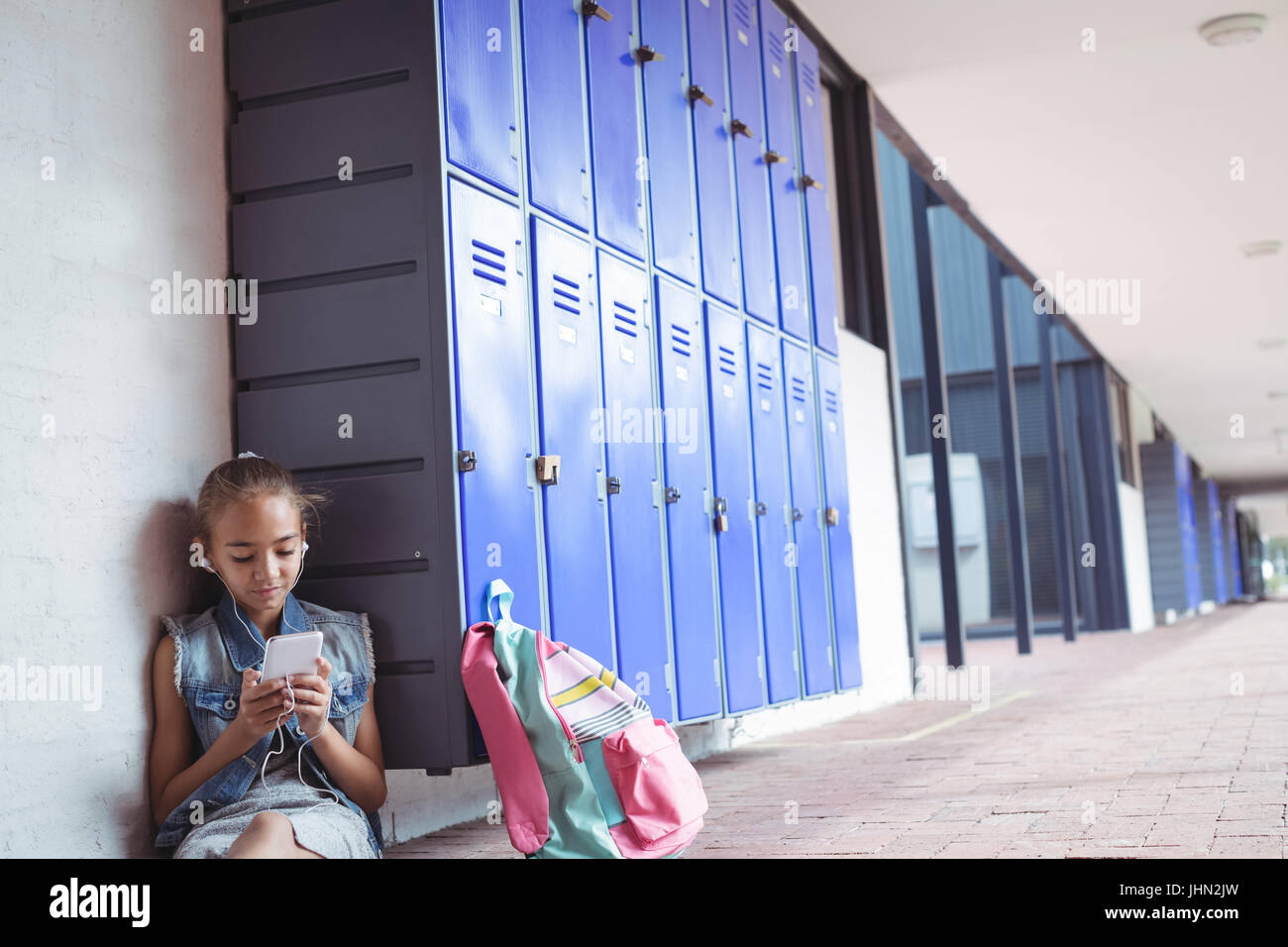 Elementary schoolgirl listening music through headphones while using