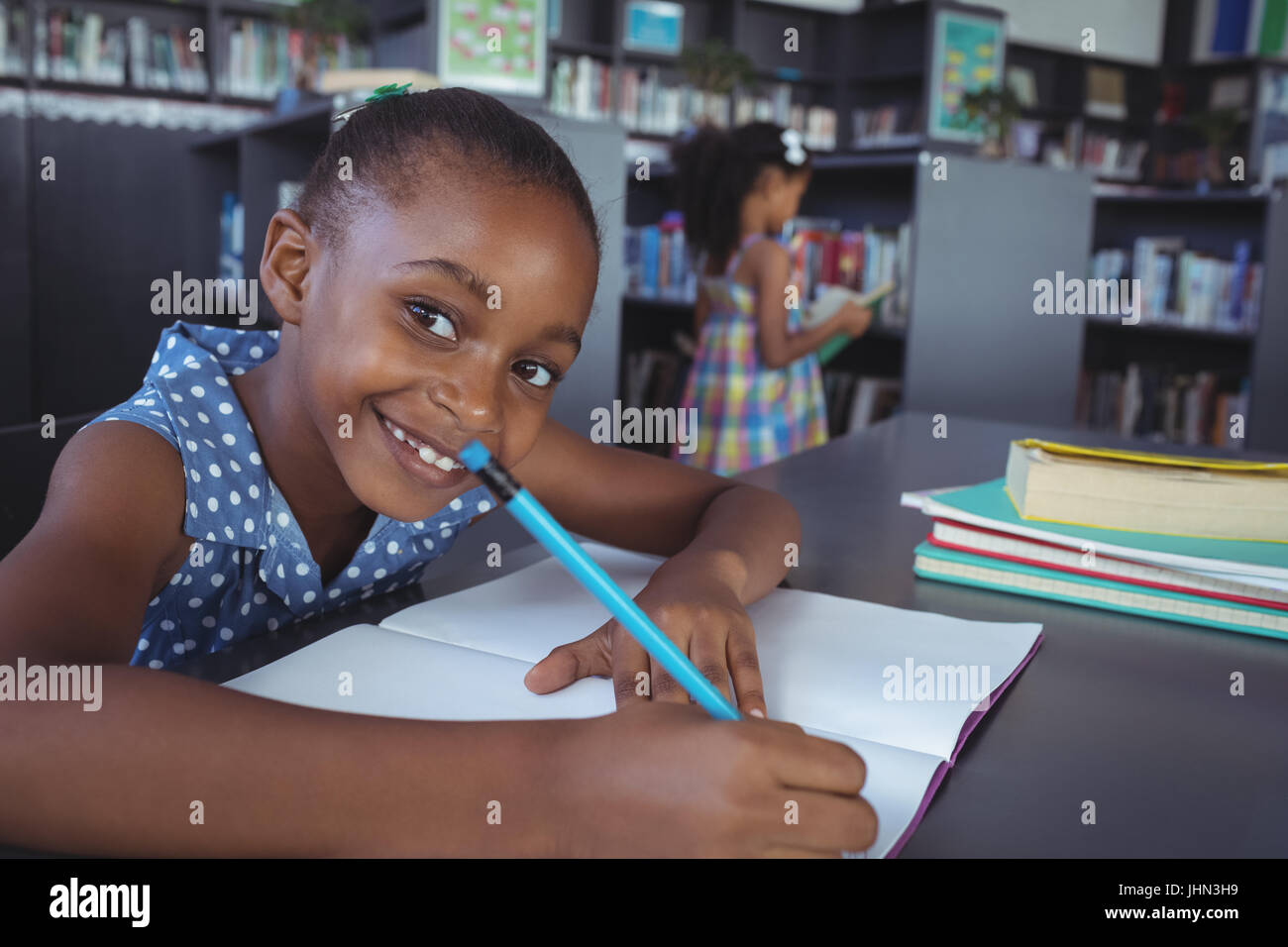 Close up portrait of smiling girl studying at desk in library Stock ...